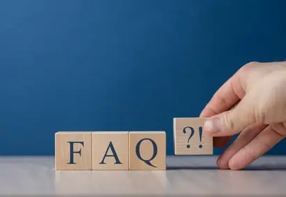Des cubes en bois formant le sigle FAQ, une main y ajoutant un cube marqué d’un point d’interrogation
